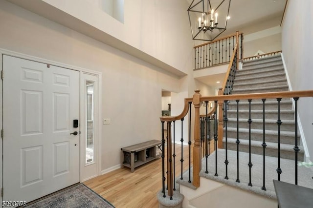 foyer featuring a notable chandelier, a towering ceiling, baseboards, and wood finished floors