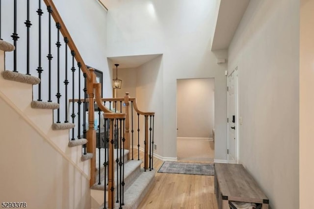 entrance foyer featuring stairs, wood finished floors, a towering ceiling, and baseboards