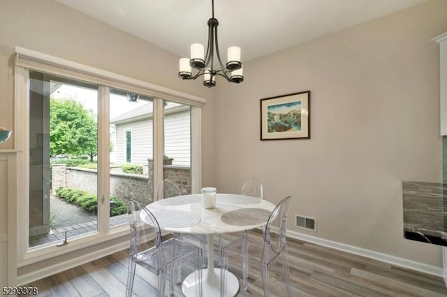 dining room featuring an inviting chandelier, visible vents, baseboards, and wood finished floors