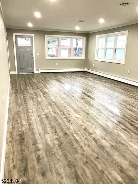 unfurnished living room featuring a healthy amount of sunlight and dark hardwood / wood-style floors