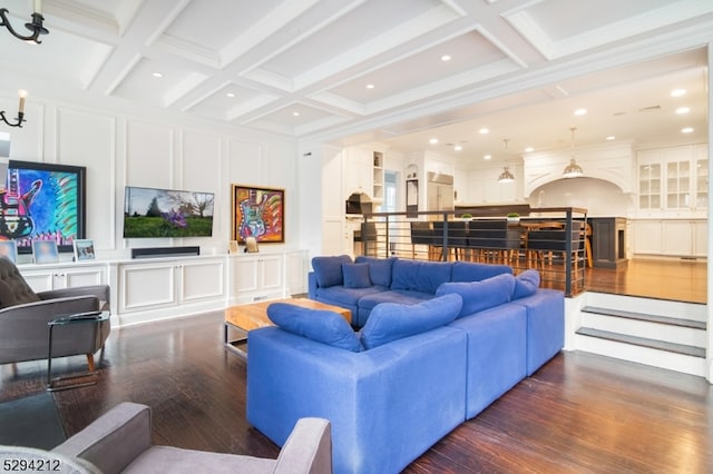 living room featuring coffered ceiling, ornamental molding, dark wood-type flooring, a notable chandelier, and beamed ceiling