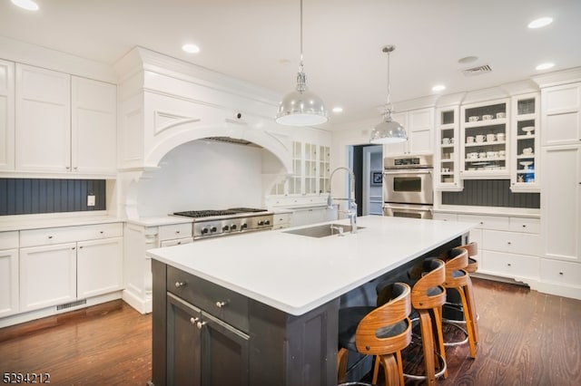 kitchen featuring appliances with stainless steel finishes, sink, white cabinetry, and an island with sink