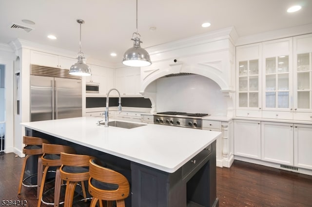 kitchen featuring sink, dark hardwood / wood-style floors, an island with sink, pendant lighting, and white cabinets