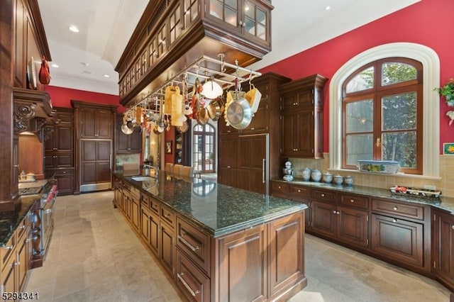 kitchen with tasteful backsplash, a center island, dark stone countertops, sink, and light tile floors