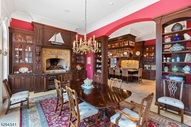 dining area featuring ornate columns, a chandelier, light tile floors, and ornamental molding