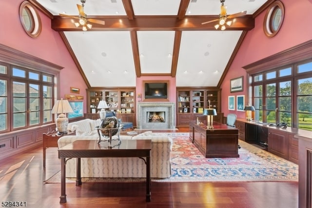 living room with a premium fireplace, ceiling fan, hardwood / wood-style floors, and beamed ceiling