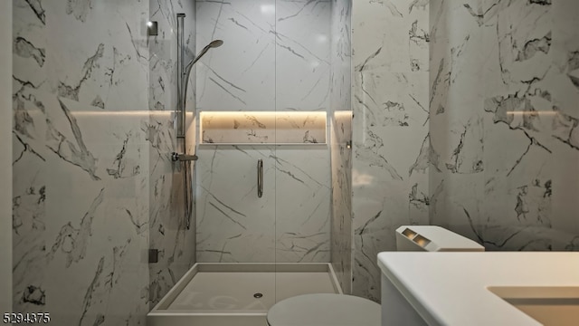 bathroom featuring tile walls, a tile shower, vanity, and toilet