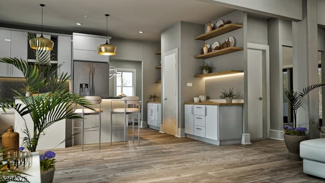 kitchen with decorative light fixtures, hardwood / wood-style floors, white cabinetry, and stainless steel fridge with ice dispenser