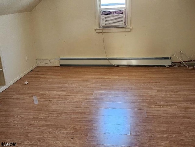 additional living space featuring vaulted ceiling, cooling unit, light wood-type flooring, and baseboard heating