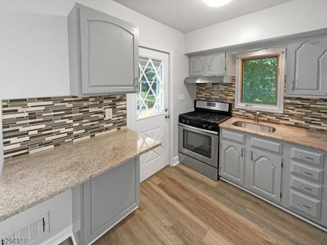 kitchen with stainless steel range with gas stovetop, tasteful backsplash, wood-type flooring, gray cabinets, and sink