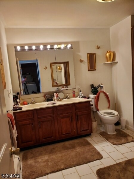 bathroom with tile flooring, double vanity, and toilet