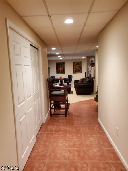 corridor featuring a paneled ceiling and tile floors