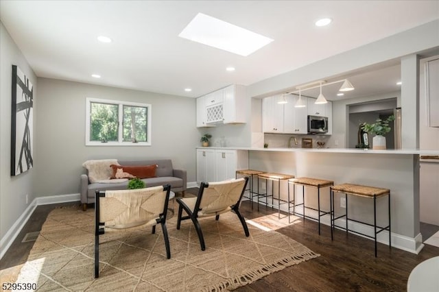 living room featuring a skylight and dark hardwood / wood-style floors