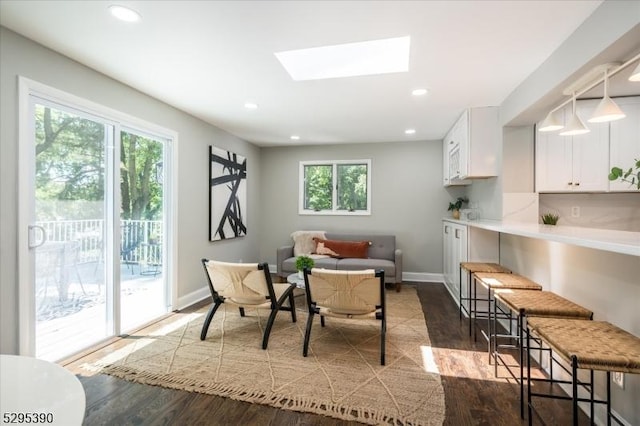 dining space with a skylight and dark hardwood / wood-style floors