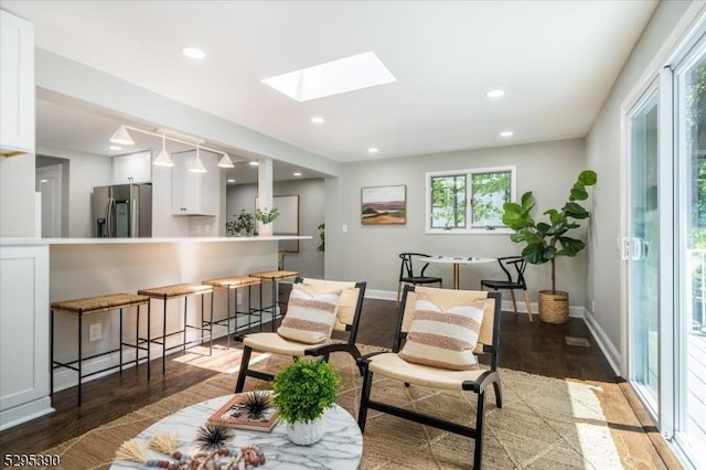 living area with a skylight and dark hardwood / wood-style flooring