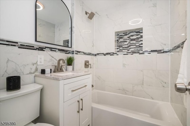 full bathroom with tile walls, vanity, tiled shower / bath combo, and toilet