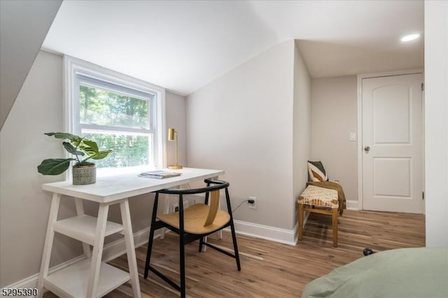 home office with light wood-type flooring and vaulted ceiling