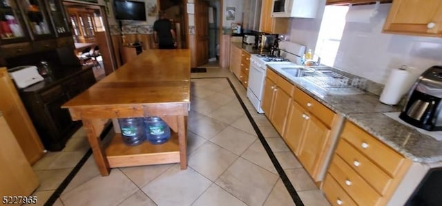 kitchen featuring white range with gas cooktop, light stone countertops, sink, and light tile patterned flooring