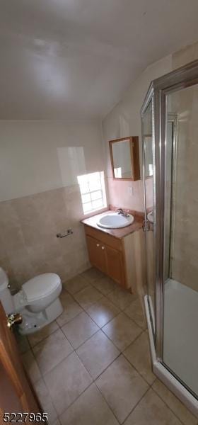 bathroom with vanity, tile walls, tile patterned flooring, toilet, and a shower with shower door