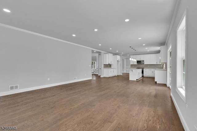 unfurnished living room with ornamental molding and dark wood-type flooring