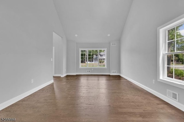 unfurnished living room with plenty of natural light, dark wood-type flooring, and high vaulted ceiling