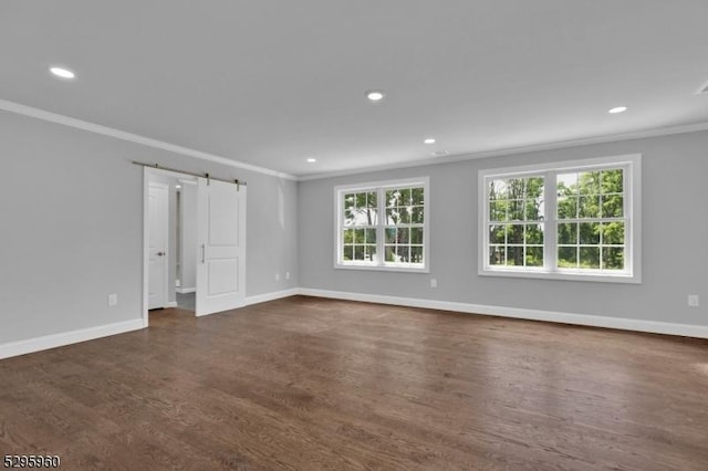 unfurnished room with a barn door, ornamental molding, dark wood-type flooring, and a wealth of natural light