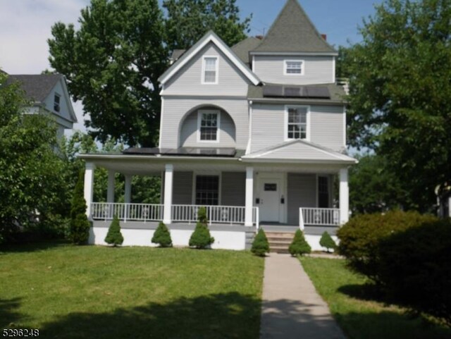 victorian house featuring a front lawn and covered porch