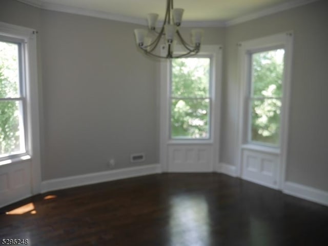 spare room with a notable chandelier, ornamental molding, and dark hardwood / wood-style flooring