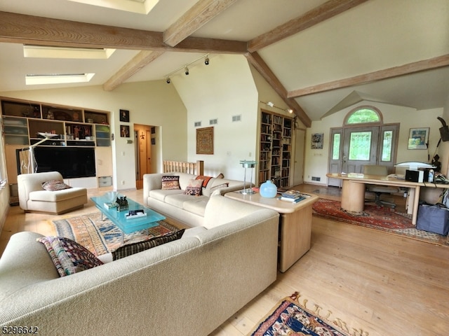 living room with beamed ceiling, light wood-type flooring, track lighting, high vaulted ceiling, and a skylight