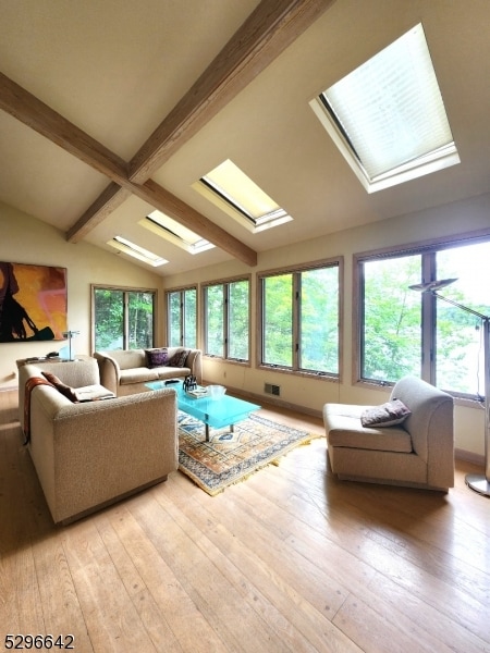 living room featuring vaulted ceiling with skylight, plenty of natural light, ceiling fan, and light hardwood / wood-style flooring