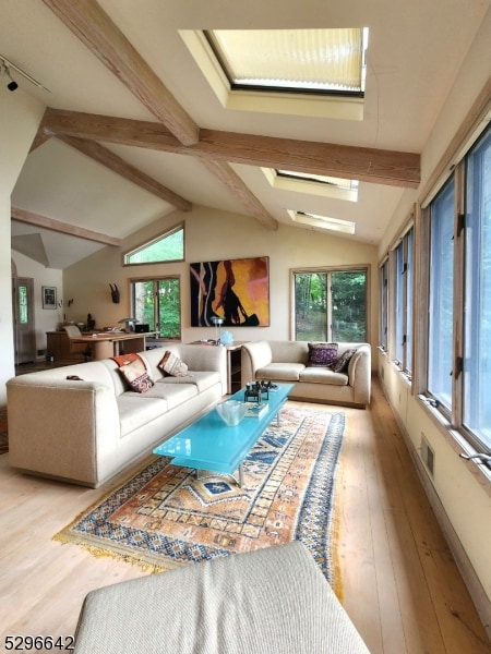 living room with a wealth of natural light, vaulted ceiling with beams, and light hardwood / wood-style flooring