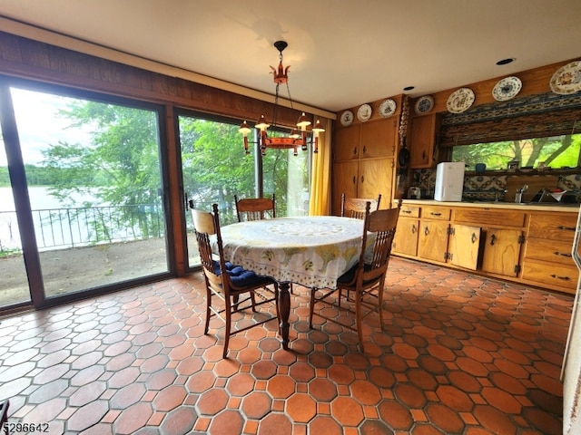 tiled dining space with a healthy amount of sunlight and a notable chandelier