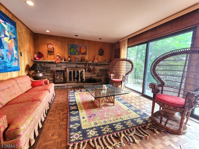 living room featuring wood walls, a stone fireplace, and dark parquet floors