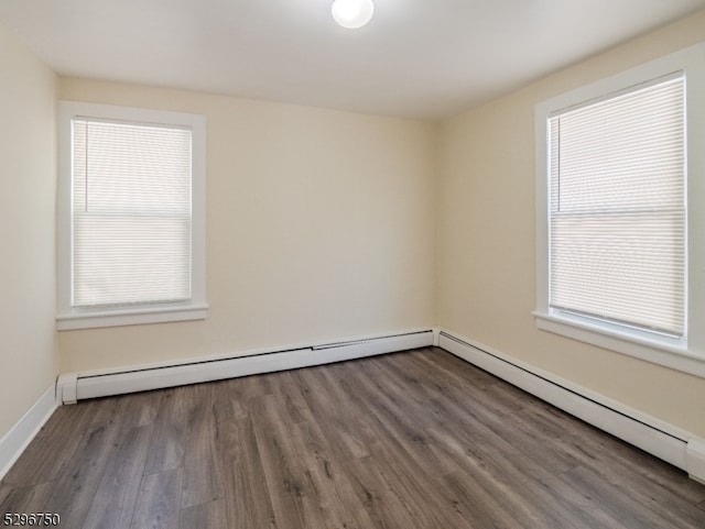 spare room featuring a baseboard heating unit and dark hardwood / wood-style flooring