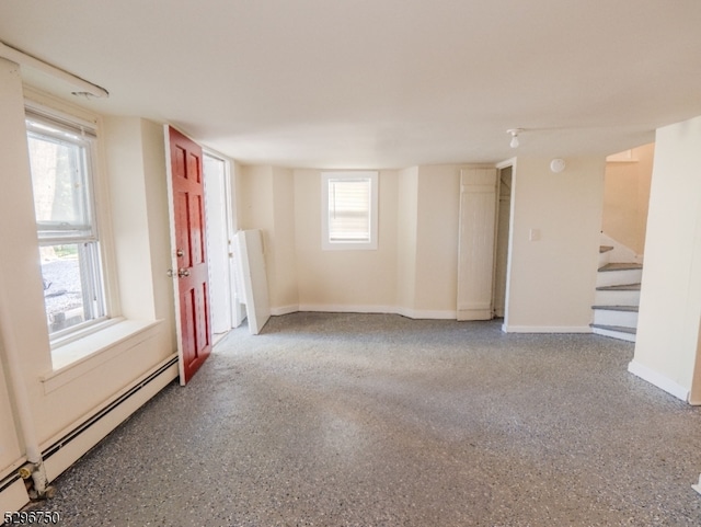 empty room featuring a baseboard heating unit and plenty of natural light