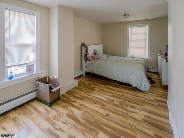 bedroom featuring light hardwood / wood-style floors, multiple windows, and baseboard heating