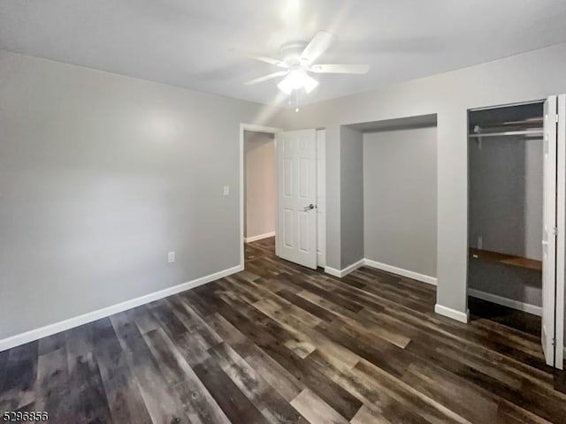 unfurnished bedroom featuring ceiling fan, dark wood-type flooring, and multiple closets