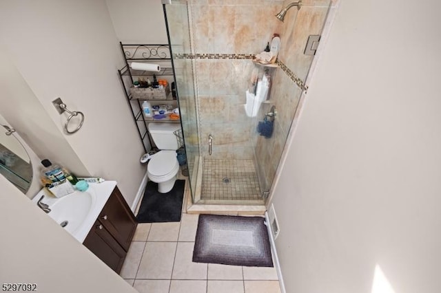 bathroom featuring tile patterned flooring, a stall shower, toilet, vanity, and baseboards