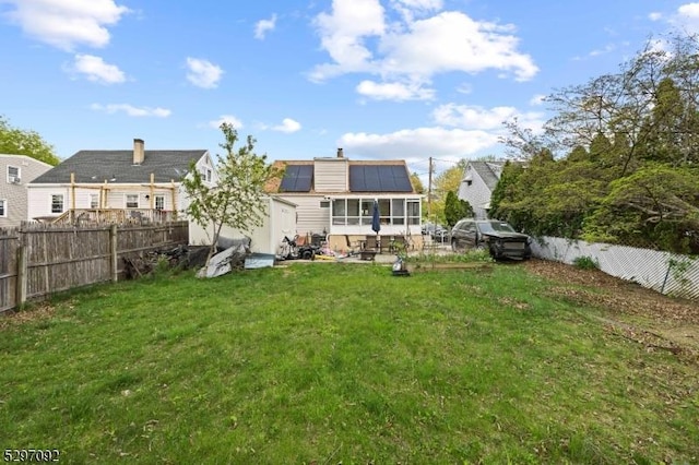back of property with roof mounted solar panels and a chimney