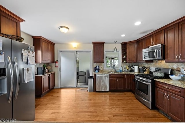 kitchen featuring stainless steel appliances, a sink, light wood-type flooring, tasteful backsplash, and recessed lighting