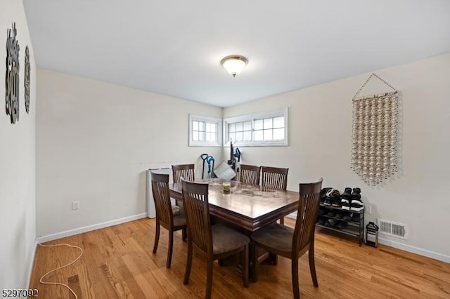 dining space featuring light wood-style flooring and baseboards