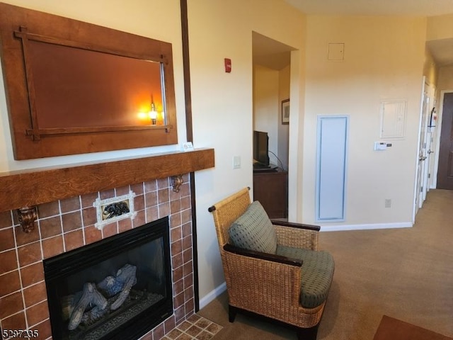 sitting room with a tiled fireplace and carpet floors