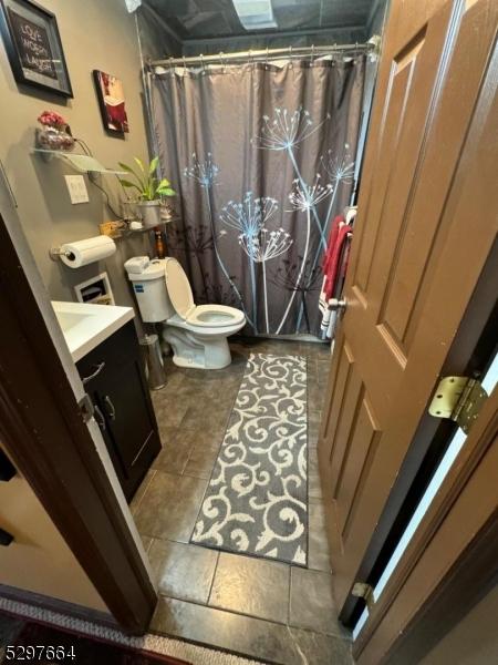 bathroom with tile patterned flooring, vanity, a shower with curtain, and toilet