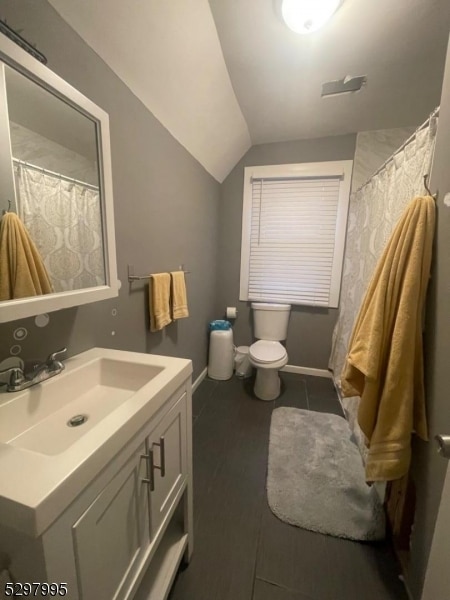 bathroom featuring lofted ceiling, toilet, and vanity