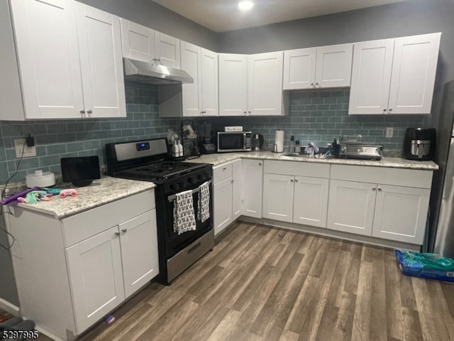 kitchen with white cabinetry, light stone counters, dark hardwood / wood-style floors, appliances with stainless steel finishes, and decorative backsplash