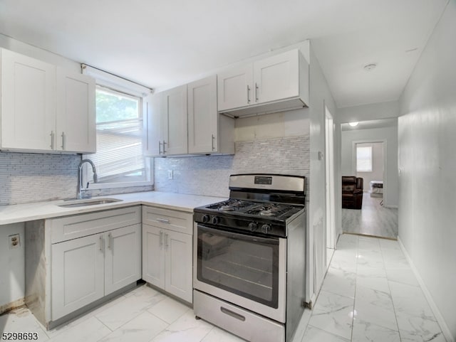 kitchen with light tile patterned floors, gas range, tasteful backsplash, and sink