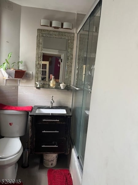 full bathroom with tile patterned floors, vanity, combined bath / shower with glass door, and toilet