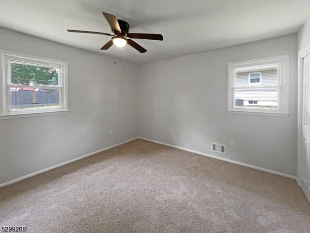 empty room featuring carpet, ceiling fan, and a wealth of natural light