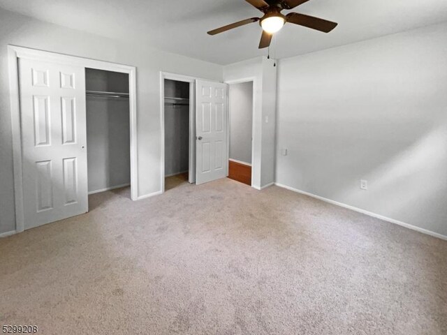 unfurnished bedroom featuring multiple closets, carpet, and ceiling fan