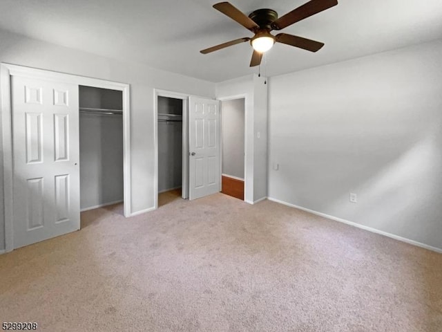 unfurnished bedroom featuring carpet floors, ceiling fan, and two closets